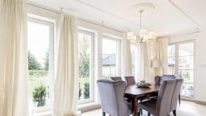 White dining room with cream drapes and dark wooden table