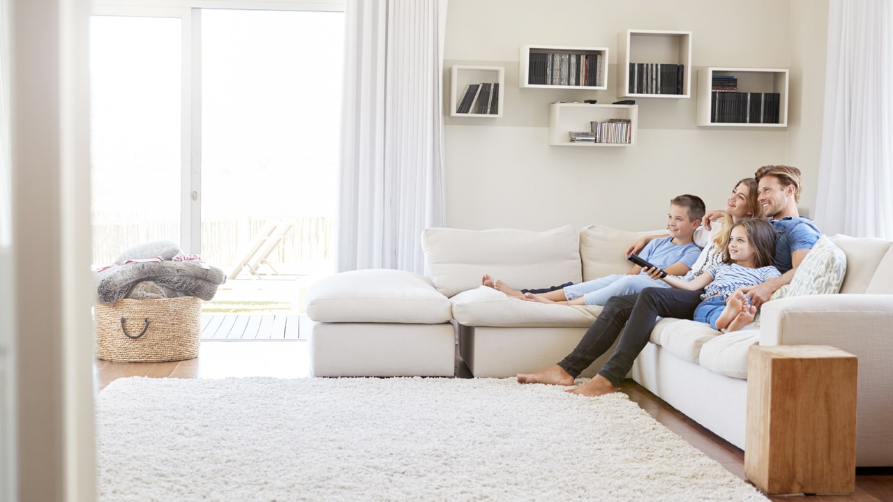 Family watching TV in room with white carpet